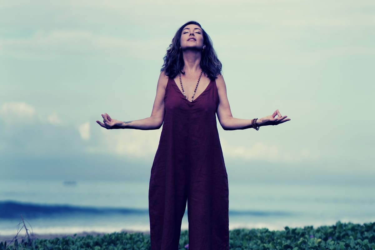 Ashlie Walker standing on a beach with her arms open to the sky