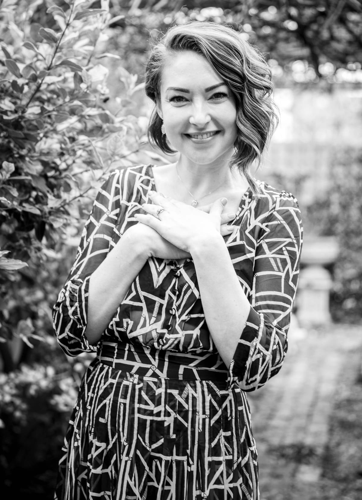Black and white portrait of Ashlie Walker smiling in a garden