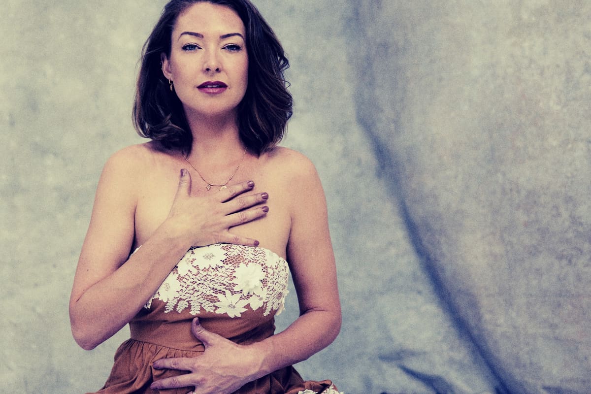 Ashlie Walker with one hand on her heart, looking calmly at the camera
