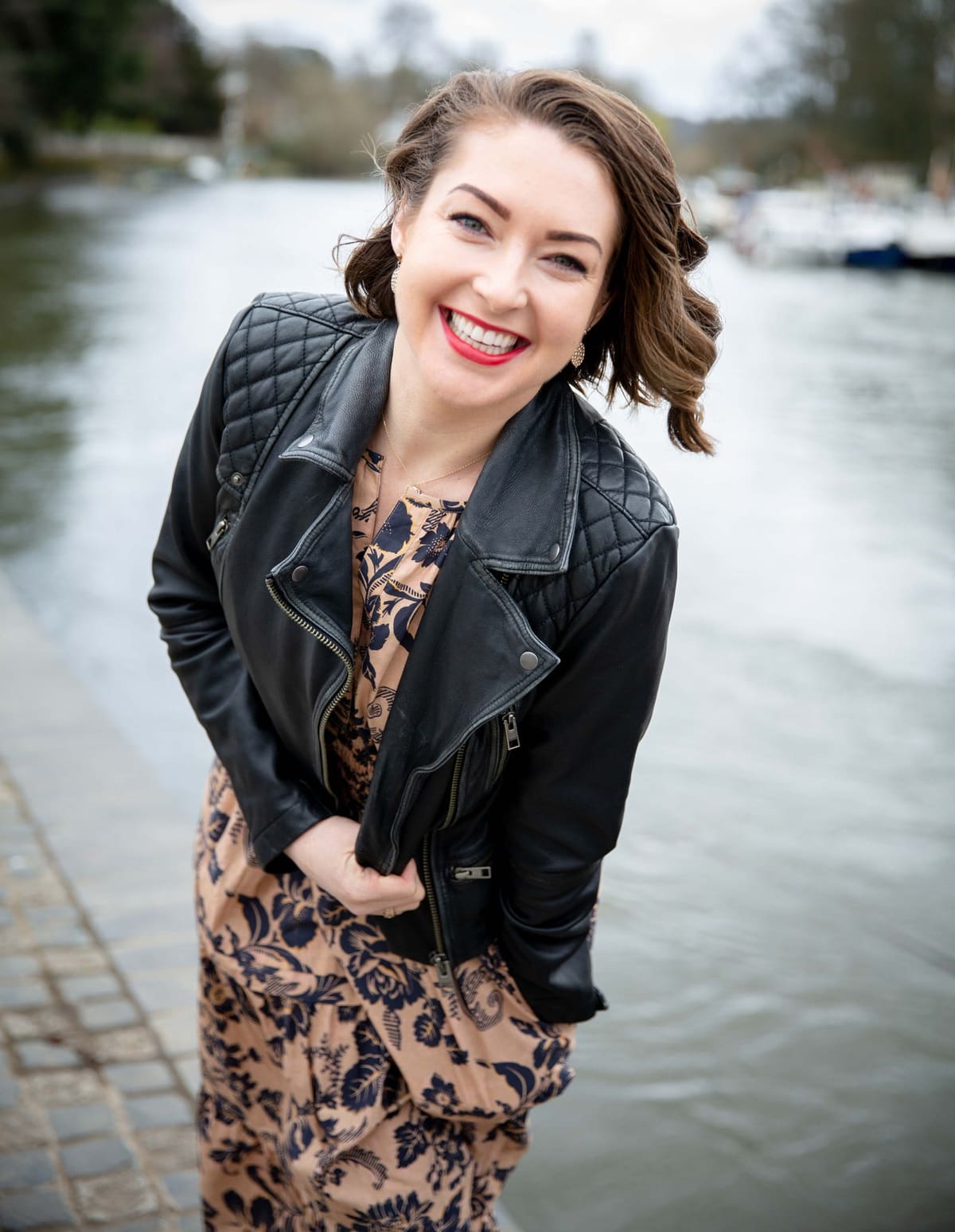 Ashlie Walker smiling by the river, wearing a black leather jacket