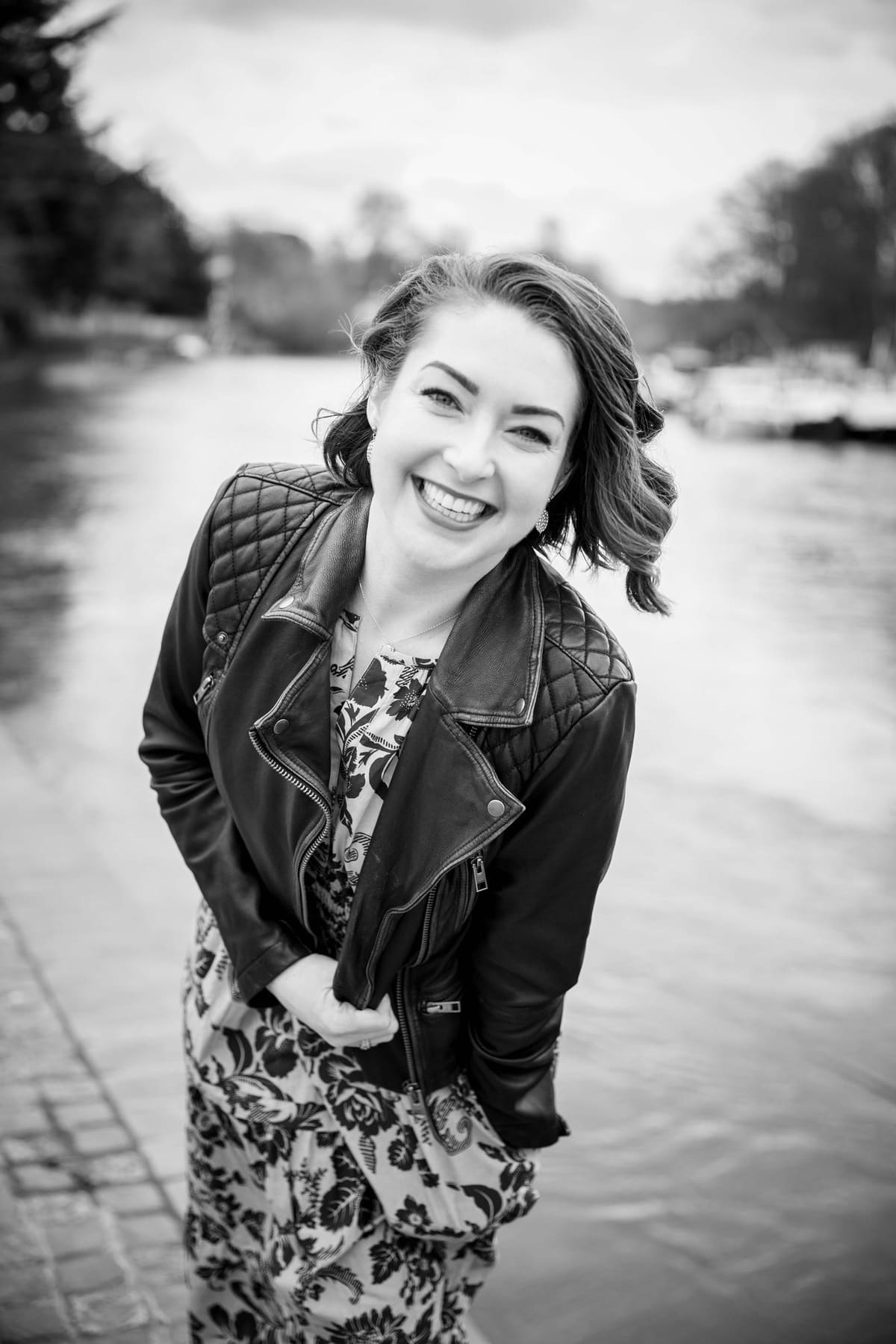 Black and white portrait of Ashlie Walker laughing beside a river