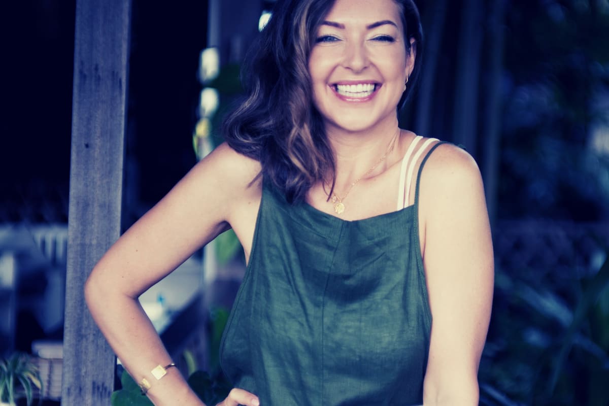 Ashlie Walker smiling, sitting outdoors in a green vest top