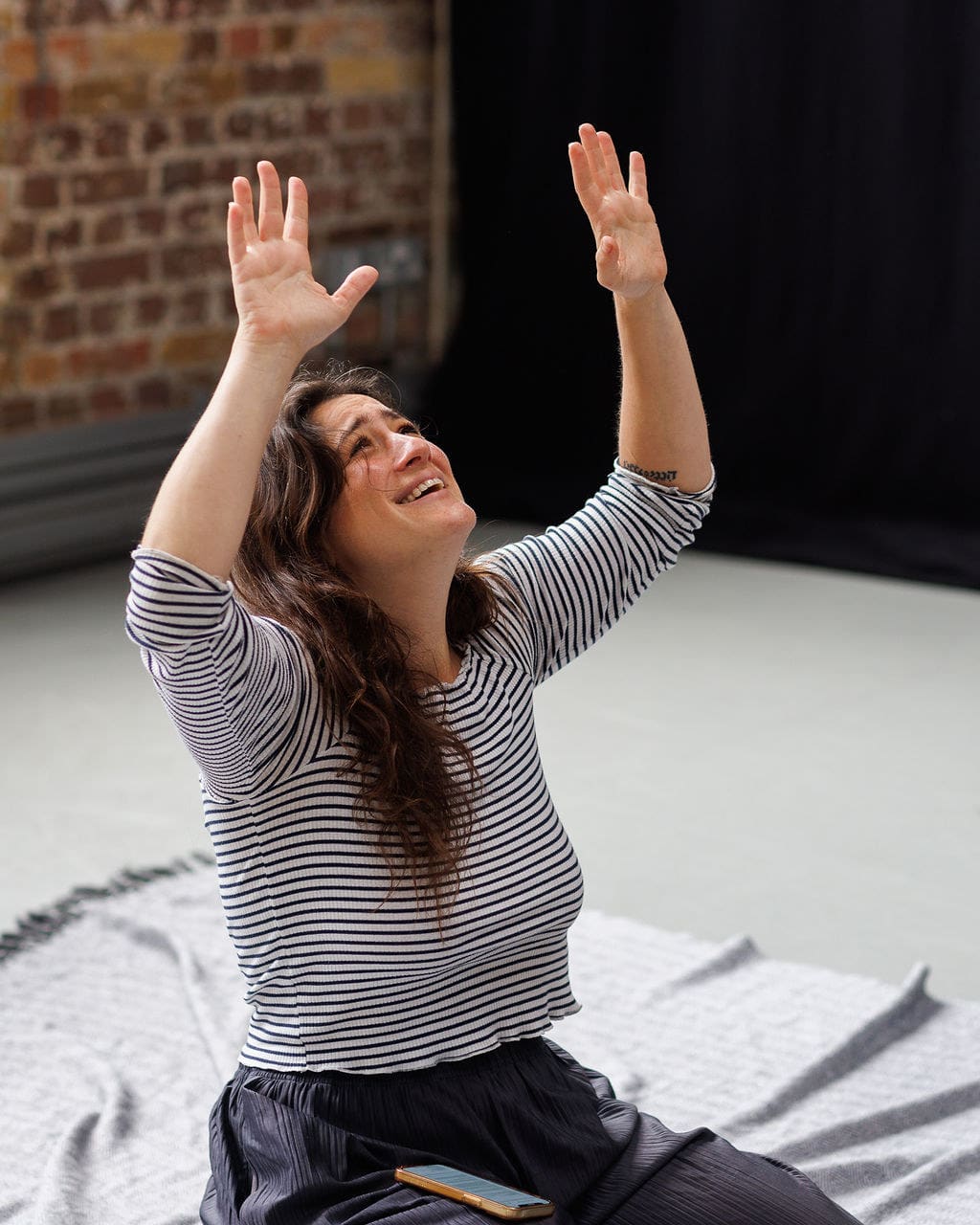 Actor Lauren Cooney raising her arms during rehearsal